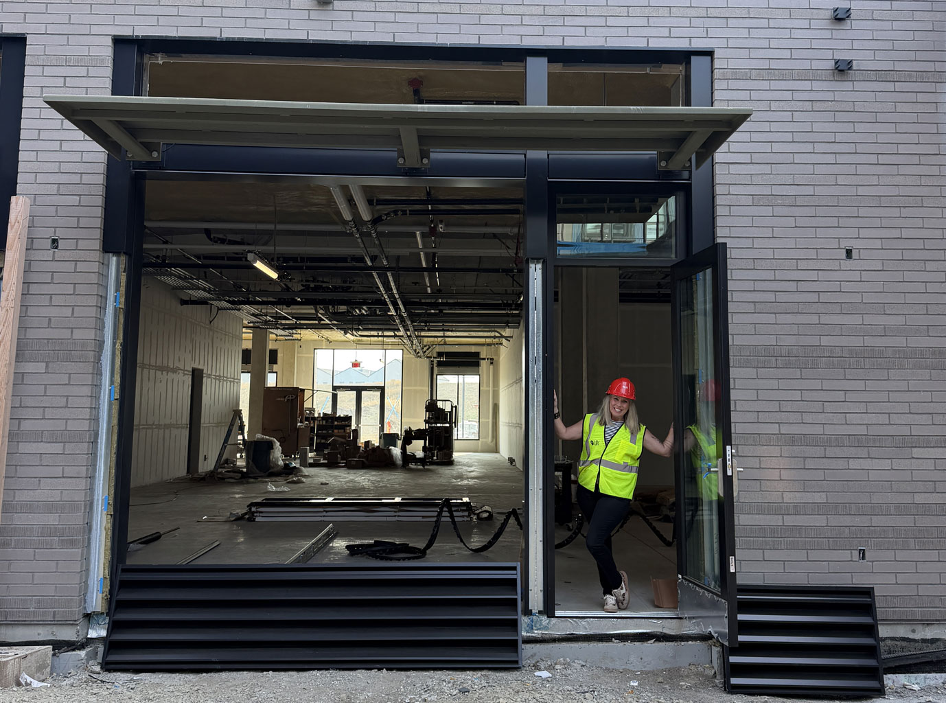 Timber & Vine owner Cloe Carlson in a hard hat at the wine bar storefront under construction at Hyas Point
